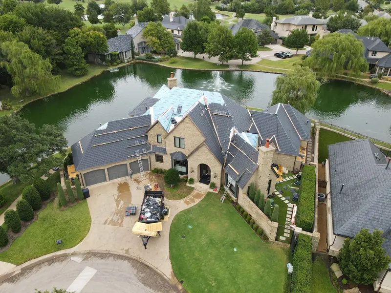 EcoStar synthetic slate install in progress with copper flashing on a large stone home