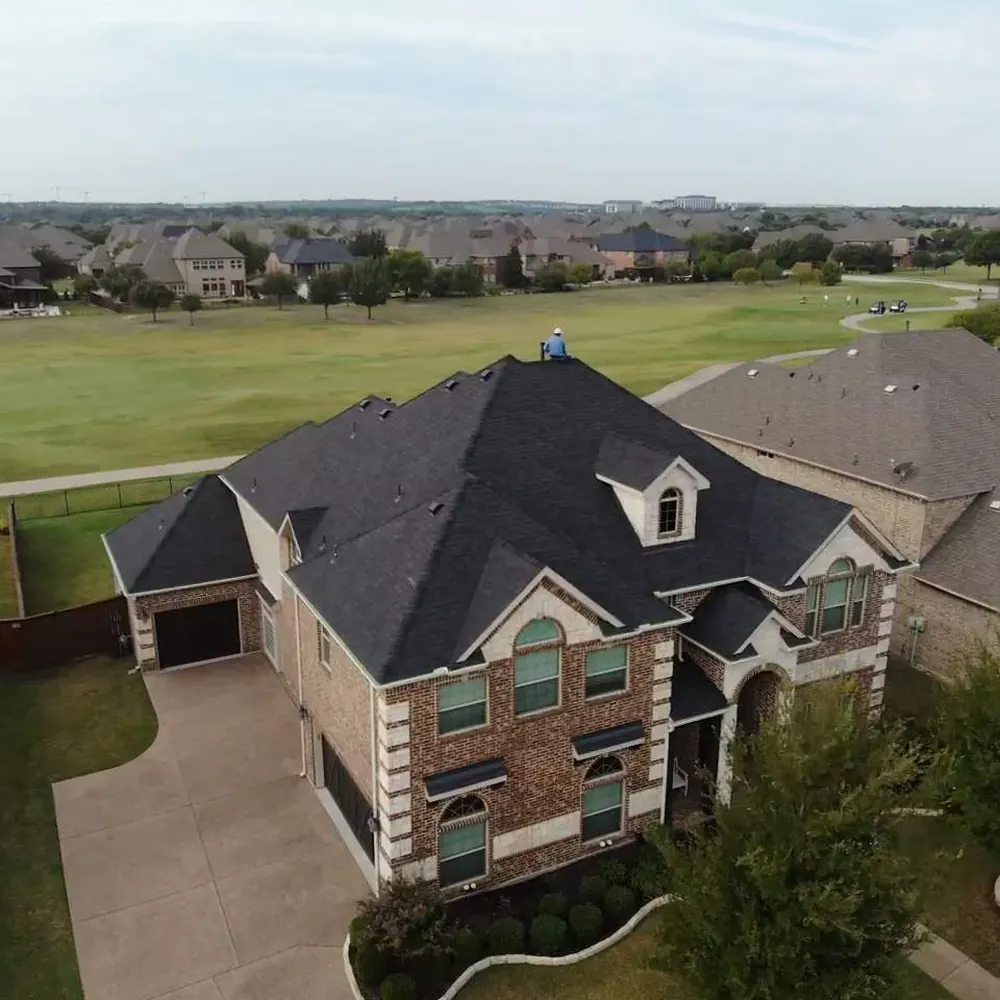 Two-story brick home on a golf course with a new dark shingle roof
