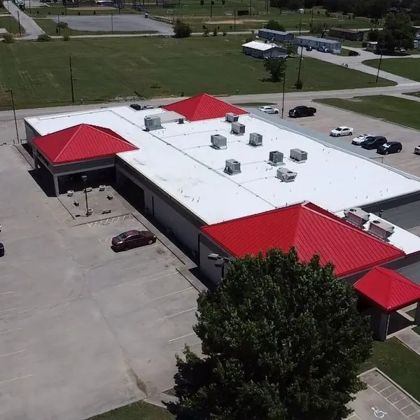 Commercial building with a white flat roof and red metal hip roofs