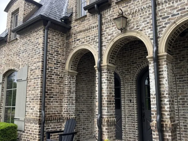 Dark bronze half-round gutters and round downspouts on a brick home