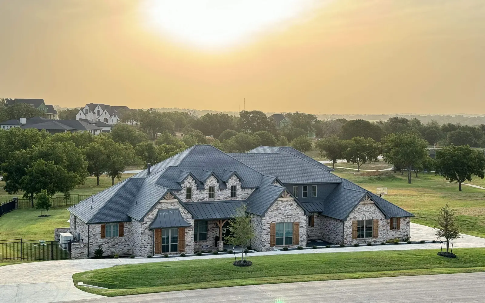 Large brick home with an F-Wave synthetic shingle roof and standing seam metal accents