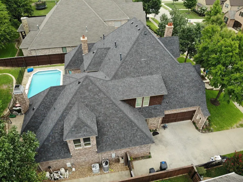 Aerial view of a completed shingle roof replacement on a large DFW home