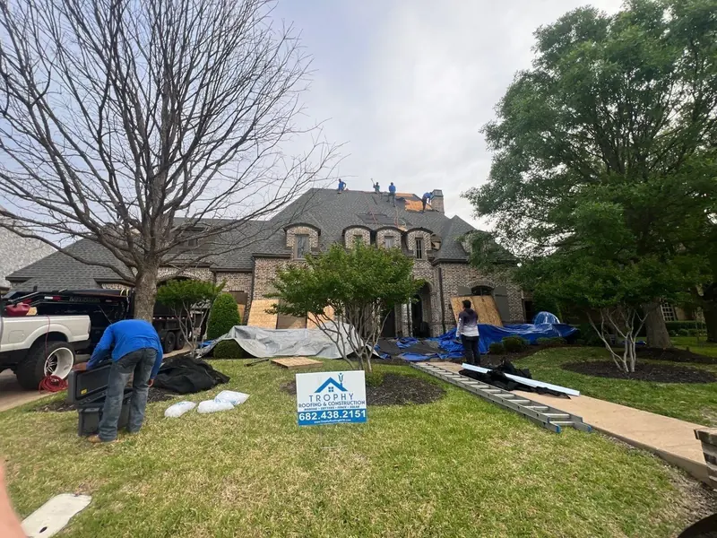 Trophy crew tearing off a storm-damaged roof on a large brick home